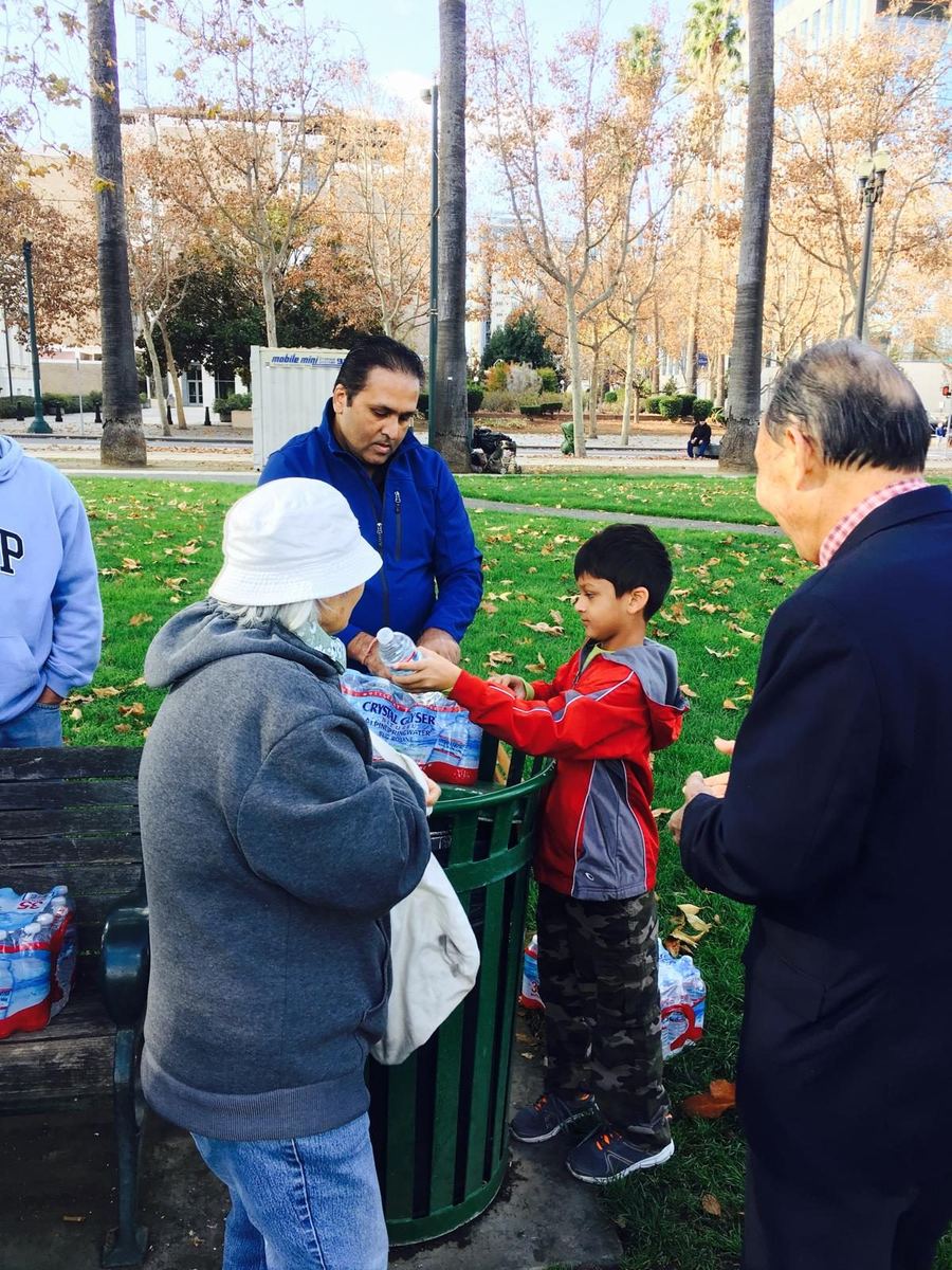 A volunteer and a child handing out bottled water at the park in the organization's earlier years