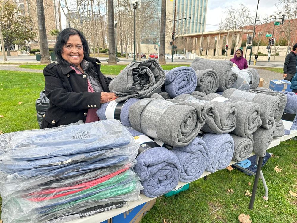 A volunteer beside stacks of rolled blankets ready to hand out
